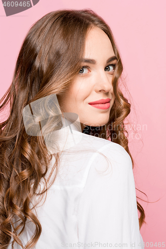 Image of The happy business woman standing and smiling against pink background.