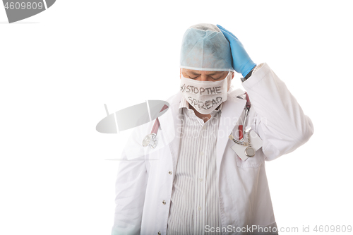 Image of Anguished overworked doctor with head in hands during pandemic