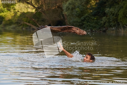 Image of Swimming in river throwing log