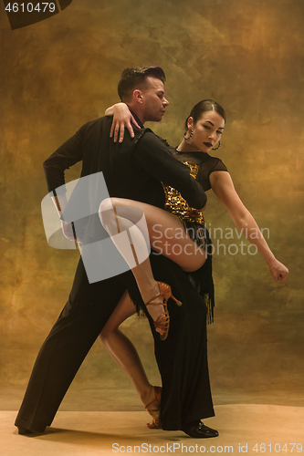 Image of Dance ballroom couple in gold dress dancing on studio background.
