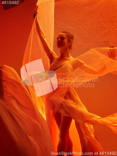 Image of Ballerina. Young graceful female ballet dancer dancing over red studio. Beauty of classic ballet.