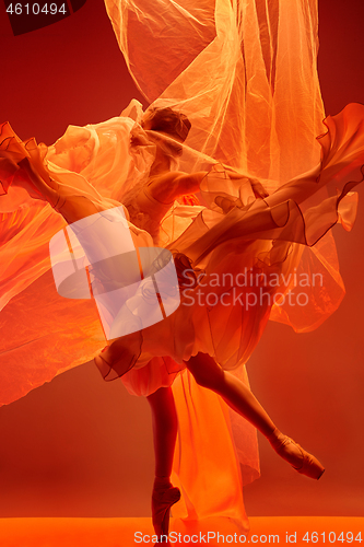 Image of Ballerina. Young graceful female ballet dancer dancing over red studio. Beauty of classic ballet.