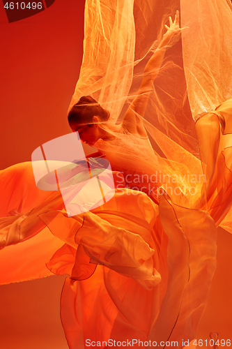 Image of Ballerina. Young graceful female ballet dancer dancing over red studio. Beauty of classic ballet.