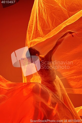 Image of Ballerina. Young graceful female ballet dancer dancing over red studio. Beauty of classic ballet.