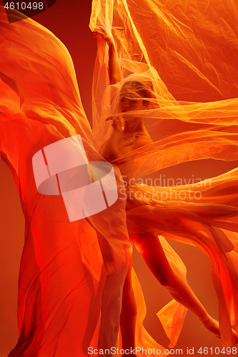 Image of Ballerina. Young graceful female ballet dancer dancing over red studio. Beauty of classic ballet.