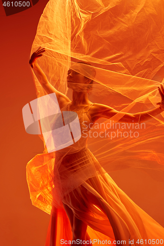 Image of Ballerina. Young graceful female ballet dancer dancing over red studio. Beauty of classic ballet.