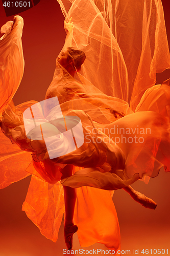 Image of Ballerina. Young graceful female ballet dancer dancing over red studio. Beauty of classic ballet.