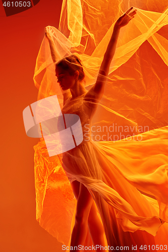 Image of Ballerina. Young graceful female ballet dancer dancing over red studio. Beauty of classic ballet.