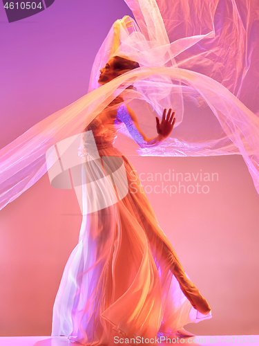 Image of Ballerina. Young graceful female ballet dancer dancing over pink studio. Beauty of classic ballet.