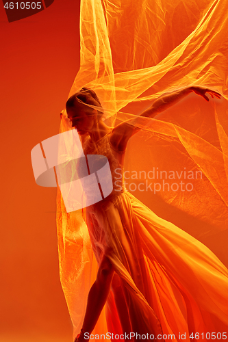 Image of Ballerina. Young graceful female ballet dancer dancing over red studio. Beauty of classic ballet.