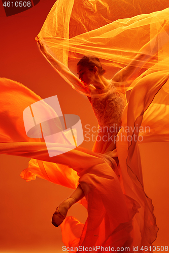 Image of Ballerina. Young graceful female ballet dancer dancing over red studio. Beauty of classic ballet.