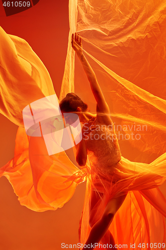 Image of Ballerina. Young graceful female ballet dancer dancing over red studio. Beauty of classic ballet.