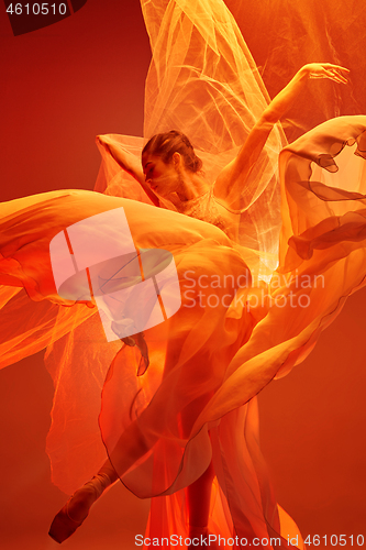 Image of Ballerina. Young graceful female ballet dancer dancing over red studio. Beauty of classic ballet.