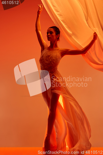 Image of Ballerina. Young graceful female ballet dancer dancing over red studio. Beauty of classic ballet.
