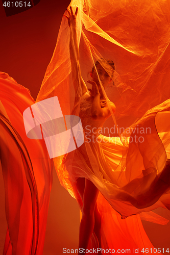 Image of Ballerina. Young graceful female ballet dancer dancing over red studio. Beauty of classic ballet.