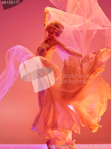 Image of Ballerina. Young graceful female ballet dancer dancing over red studio. Beauty of classic ballet.