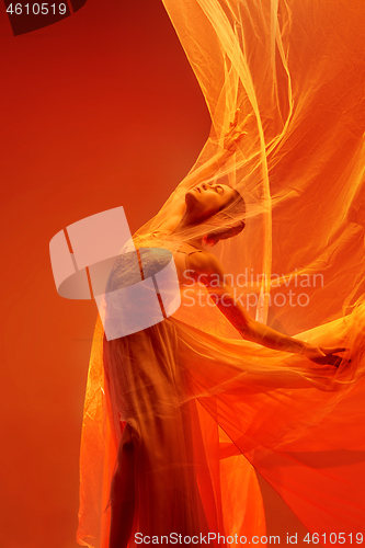 Image of Ballerina. Young graceful female ballet dancer dancing over red studio. Beauty of classic ballet.