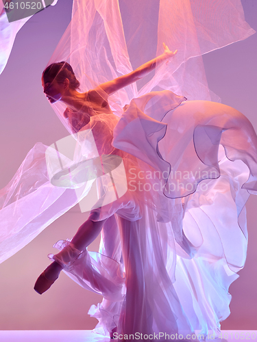 Image of Ballerina. Young graceful female ballet dancer dancing over pink studio. Beauty of classic ballet.