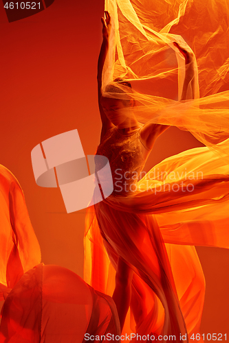 Image of Ballerina. Young graceful female ballet dancer dancing over red studio. Beauty of classic ballet.