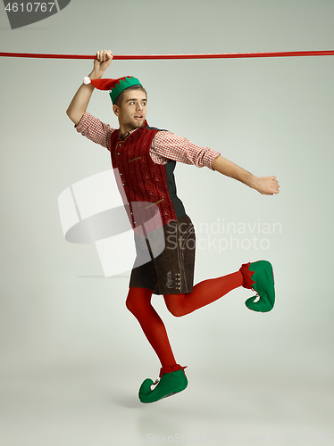 Image of friendly man dressed like a funny gnome posing on gray background