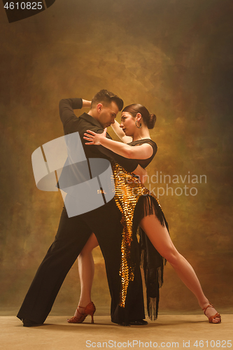 Image of Dance ballroom couple in gold dress dancing on studio background.