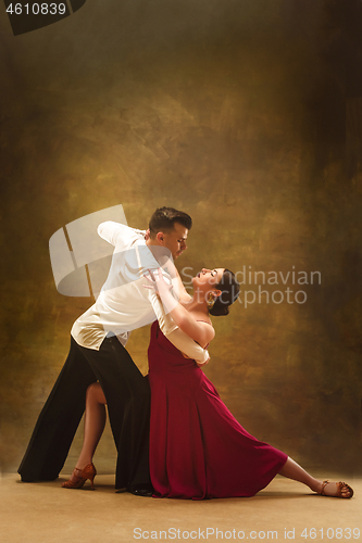 Image of Dance ballroom couple in gold dress dancing on studio background.