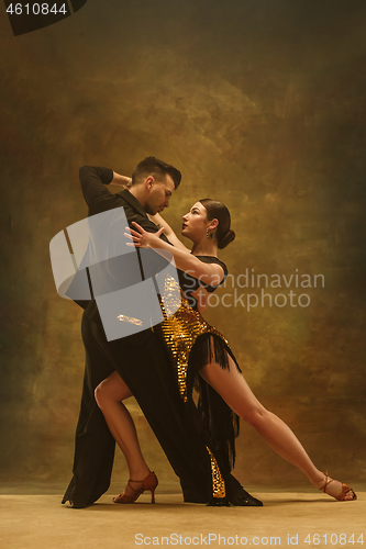 Image of Dance ballroom couple in gold dress dancing on studio background.