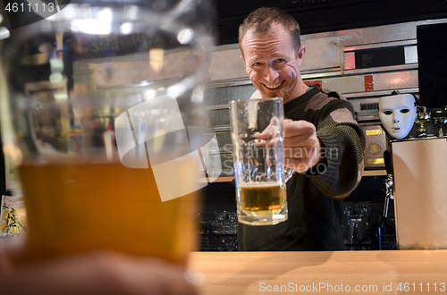 Image of Bartender cheers with a beer in the bar