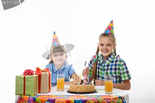 Image of Two girls at the festive table ready to eat cake