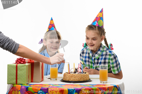 Image of Mom\'s hand sets fire to candles on a birthday cake