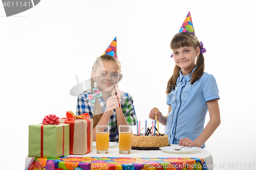 Image of Two girls put candles in a birthday cake