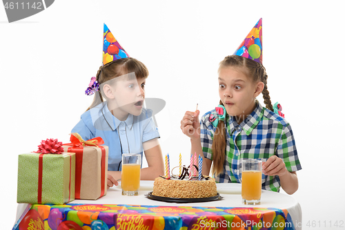 Image of Children funny look at a lit match sitting at the festive table