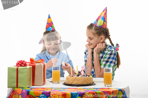 Image of Children light a match to light candles on a cake on a holiday
