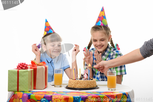 Image of Children rejoice when mom lights candles at the birthday festive table