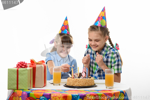 Image of Children independently light candles on a pie at the festive table