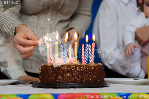 Image of Mom lights candles on a cake at a birthday party