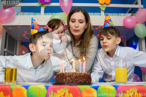 Image of Family blowing candles on birthday cake