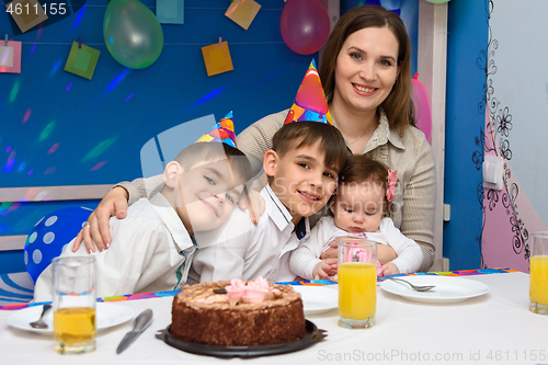 Image of Happy family hugs mom at birthday party