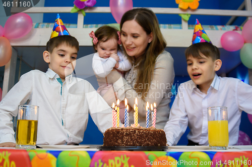 Image of Children prepare to put out candles on a festive cake