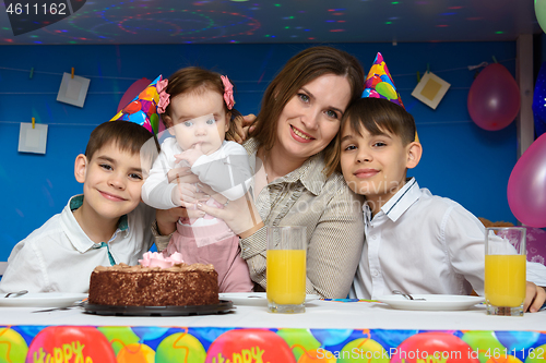 Image of Mom, two sons and a baby daughter at the festive table in the home interior