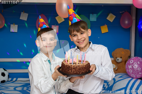 Image of Two brothers hold a holiday cake at a holiday