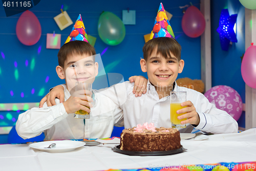 Image of Two boys eat cake and drink juice at a birthday party