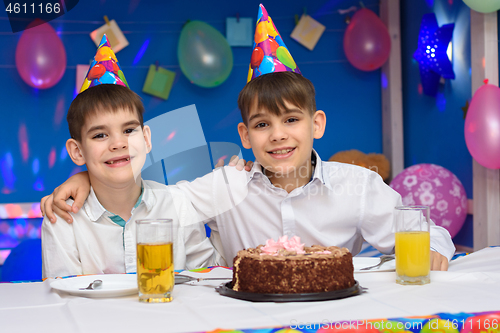 Image of Two brothers hug each other while sitting at the festive table