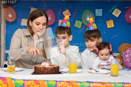 Image of Mom cuts a birthday cake with her children