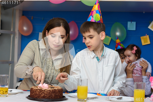 Image of Mother and son cut a cake in honor of the birthday