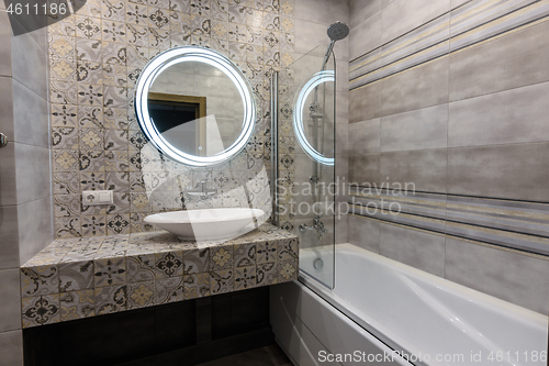 Image of Washbasin, mirror and bathtub in the interior of a modern bathroom