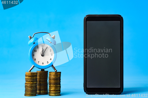 Image of Business items - watch, stack of coins and phone on a blue background