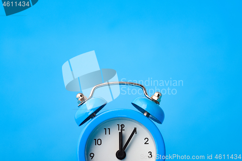 Image of Fragment of an alarm clock and empty space above it, blue background