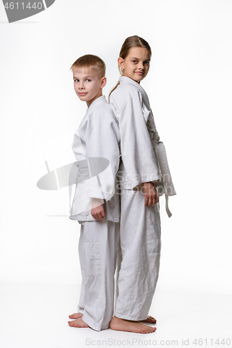 Image of Boy and girl in sports kimono stand with their backs to each other