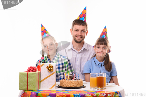 Image of Happy dad and two daughters at the festive table in honor of the birthday